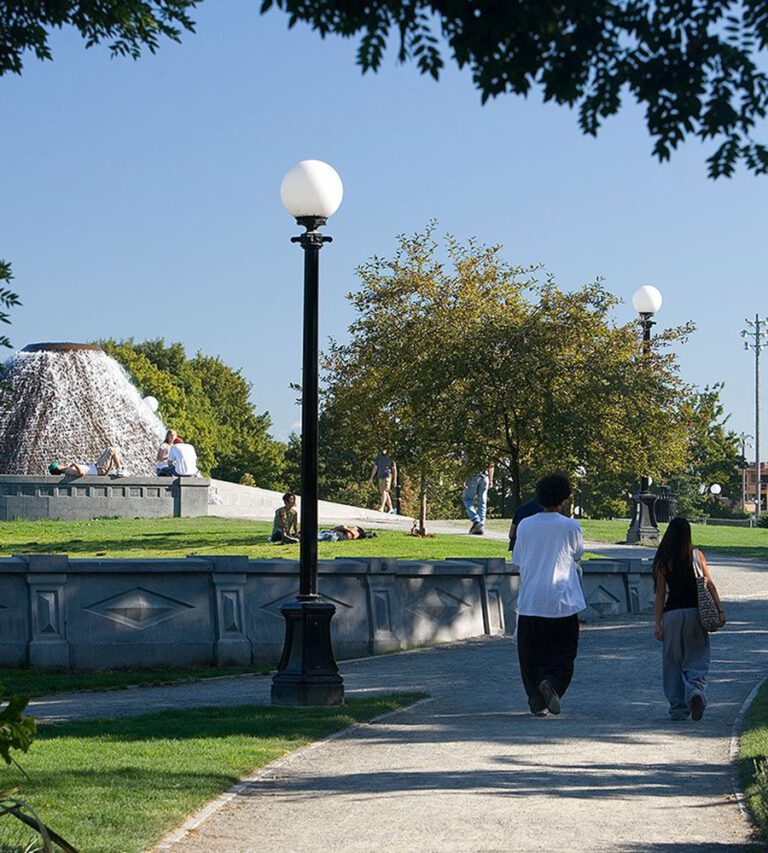 Two people walk together on a path through Cal Anderson park past the iconic fountain