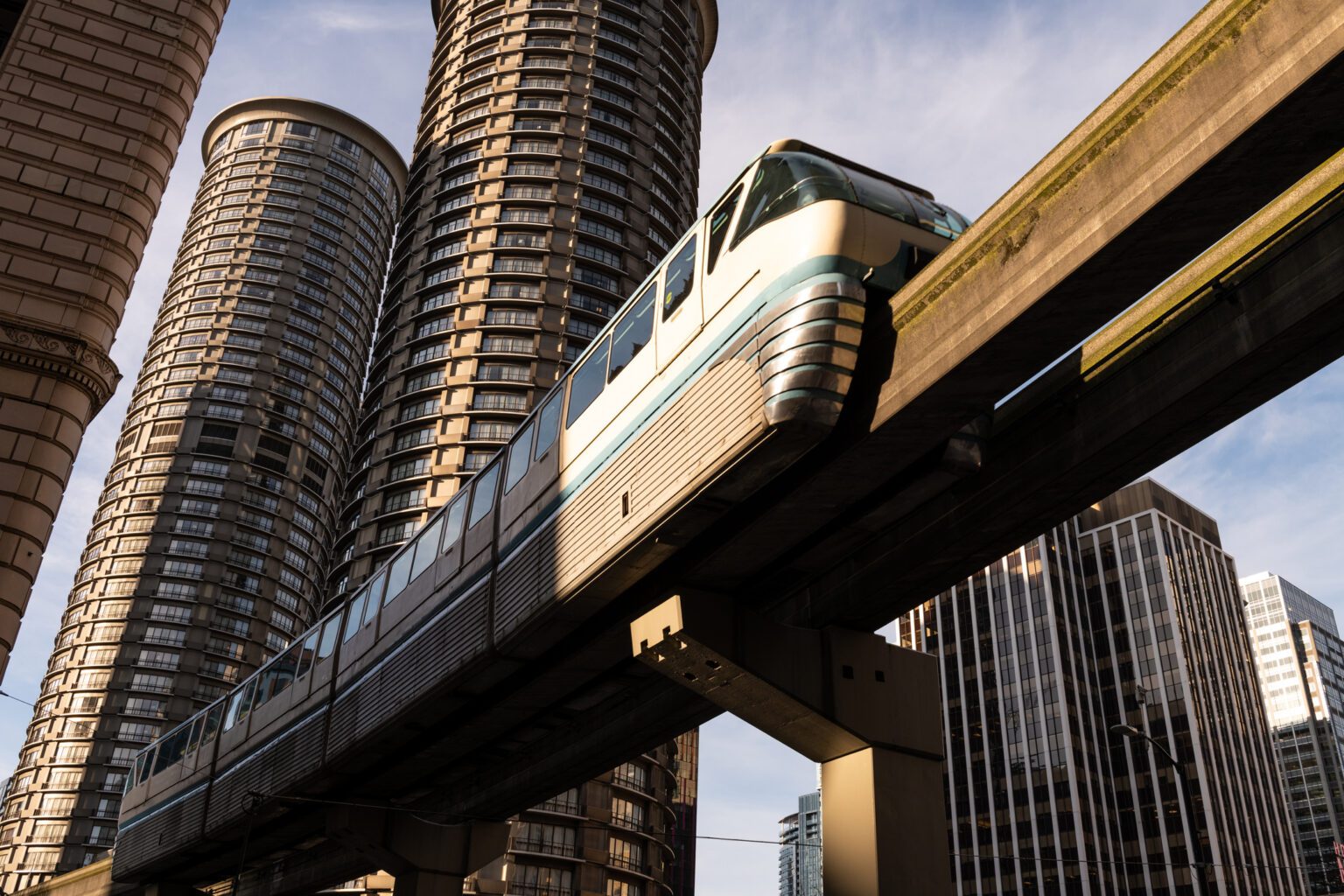 The Seattle monorail passes overhead with circular partment buildings in the background at sunset