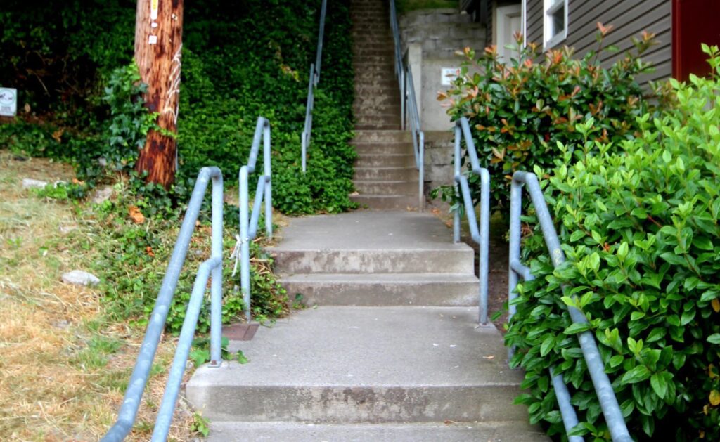 A tidy set of stairs with cool blue railing alongside an apartment building