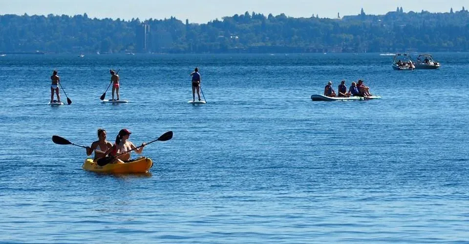 People paddleboarding, kayaking, and boating on a lake