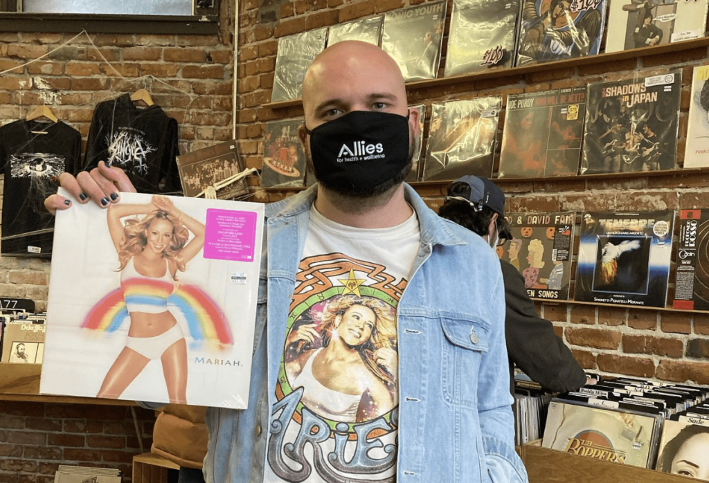 A customer holds up a Mariah Carey record while wearing a Mariah shirt inside of Spin Cycle