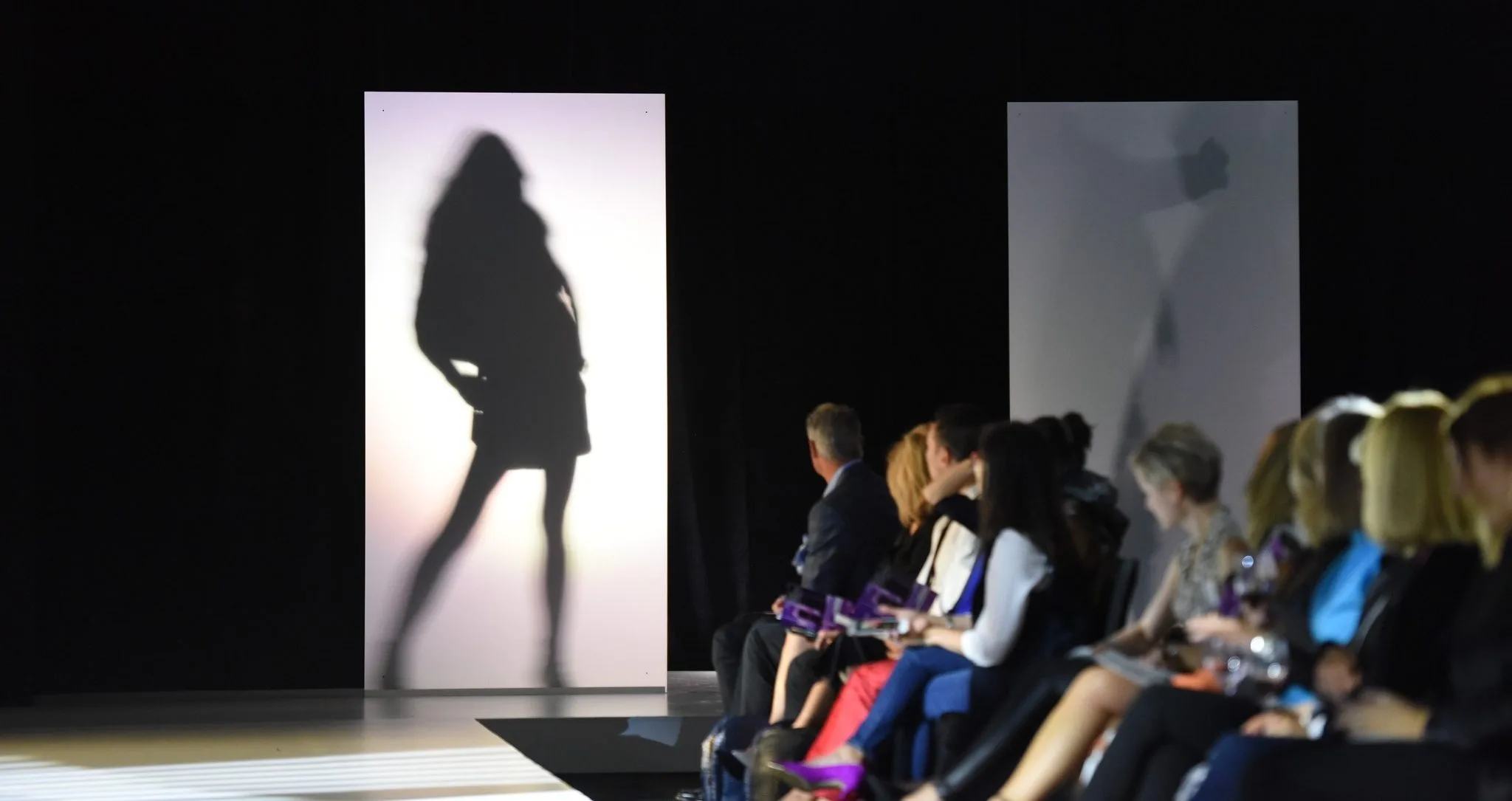 Front row at Bellevue Fashion Week looks at the shadowy figure of a model