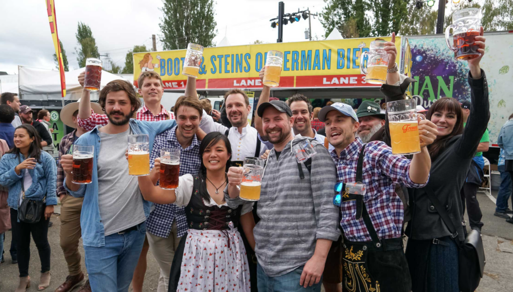 A group of people holding up tankards of beer at Fremont Oktoberfest