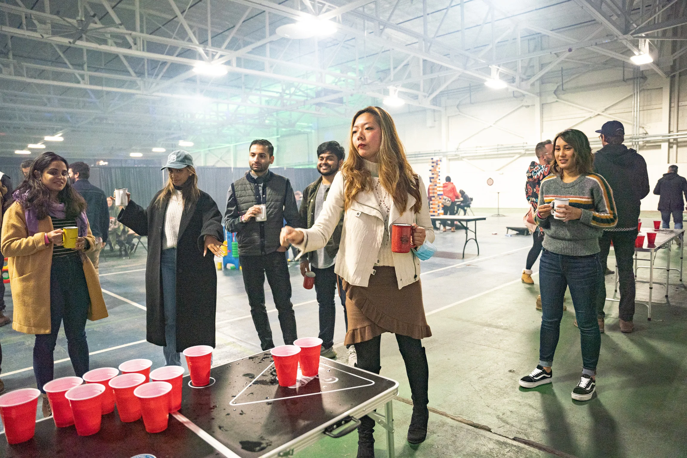 A group of people playing beer pong