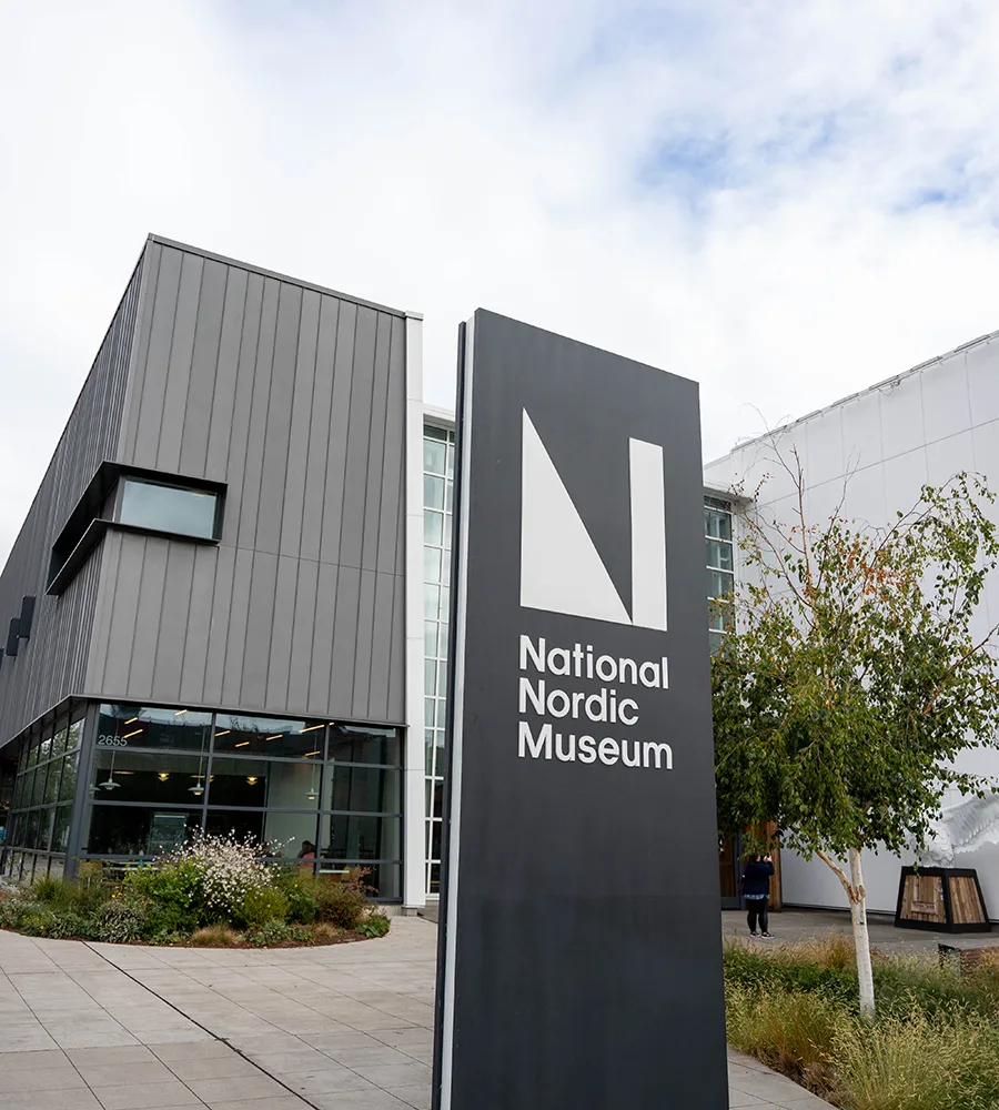 The exterior of National Nordic Museum with its sign in the foreground on a cloudy day