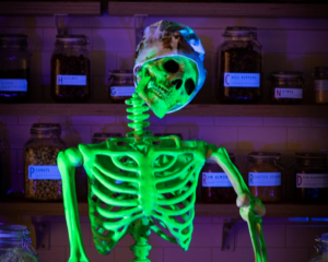 A neon green skeleton sits in a chocolate factory