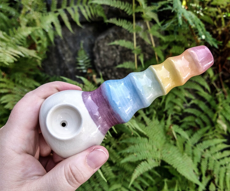 Cannabis pottery from Foggy Moon. A hand holds a ceramic piece with a rainbow tip.