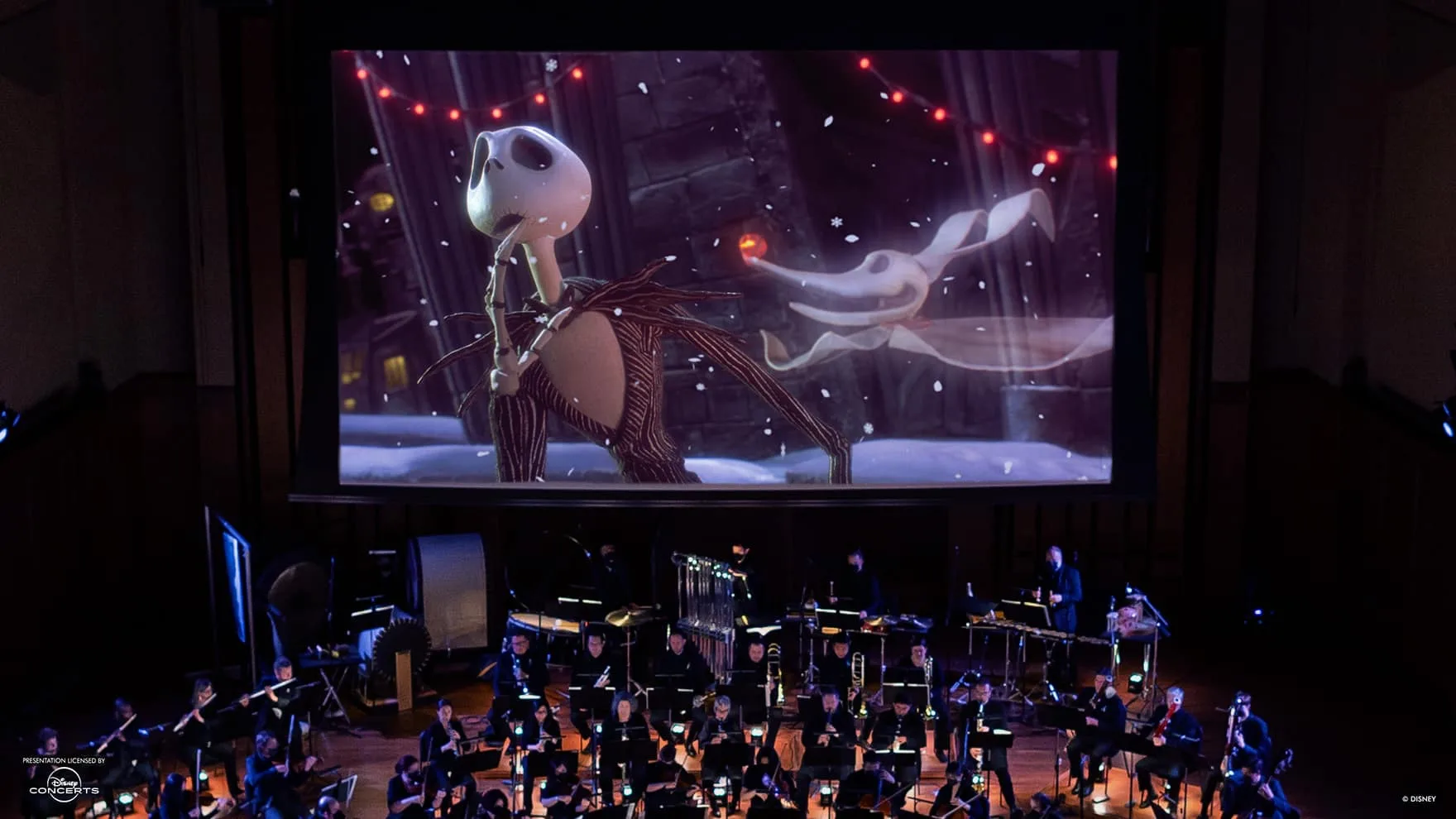An orchestra plays against a giant screen playing The Nightmare Before Christmas.