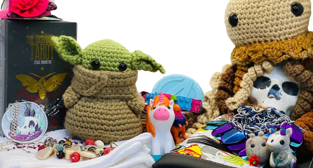 A collection of geeky gifts including a knitted baby yoda and a squishy unicorn