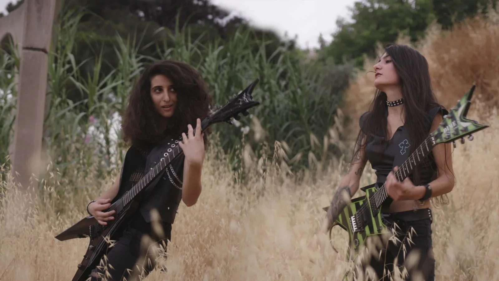 Lilas and Shery from the band, Slave to Sirens, play electric guitars in a field of wheat