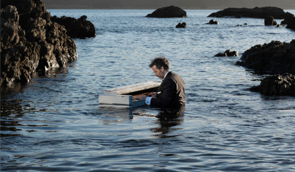 Bret McKenzie plays a piano submerged in water