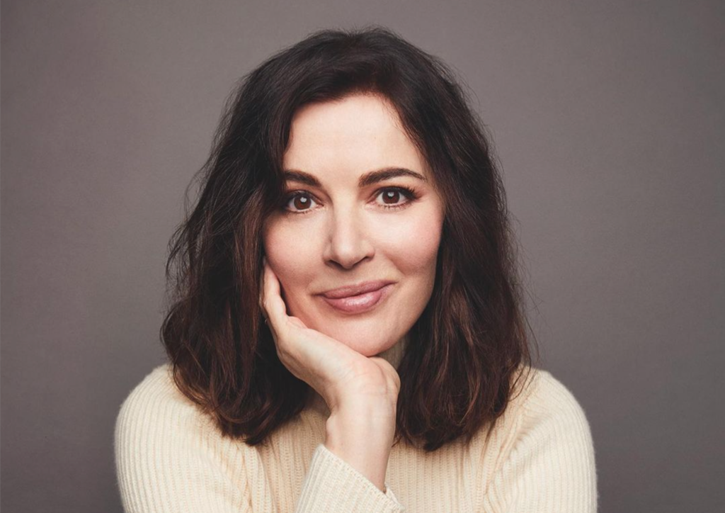 Food writer and TV cook, Nigella Lawson rests her chin in her hand against a gray background
