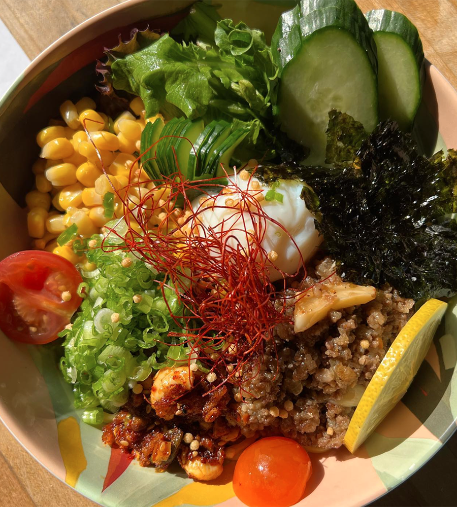Wagyu Suliyaki beef bowl with cucumbers, corn, lettuce, green onions, sliced tomatoes, and an onsen egg from Hi Life.