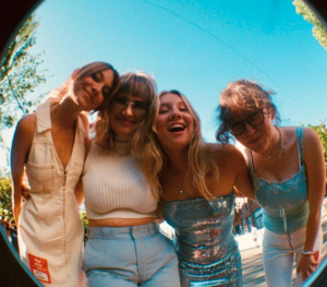A photo of the band THEM laughing, with their arms slung over each other's shoulders. Shot through a fisheye lens