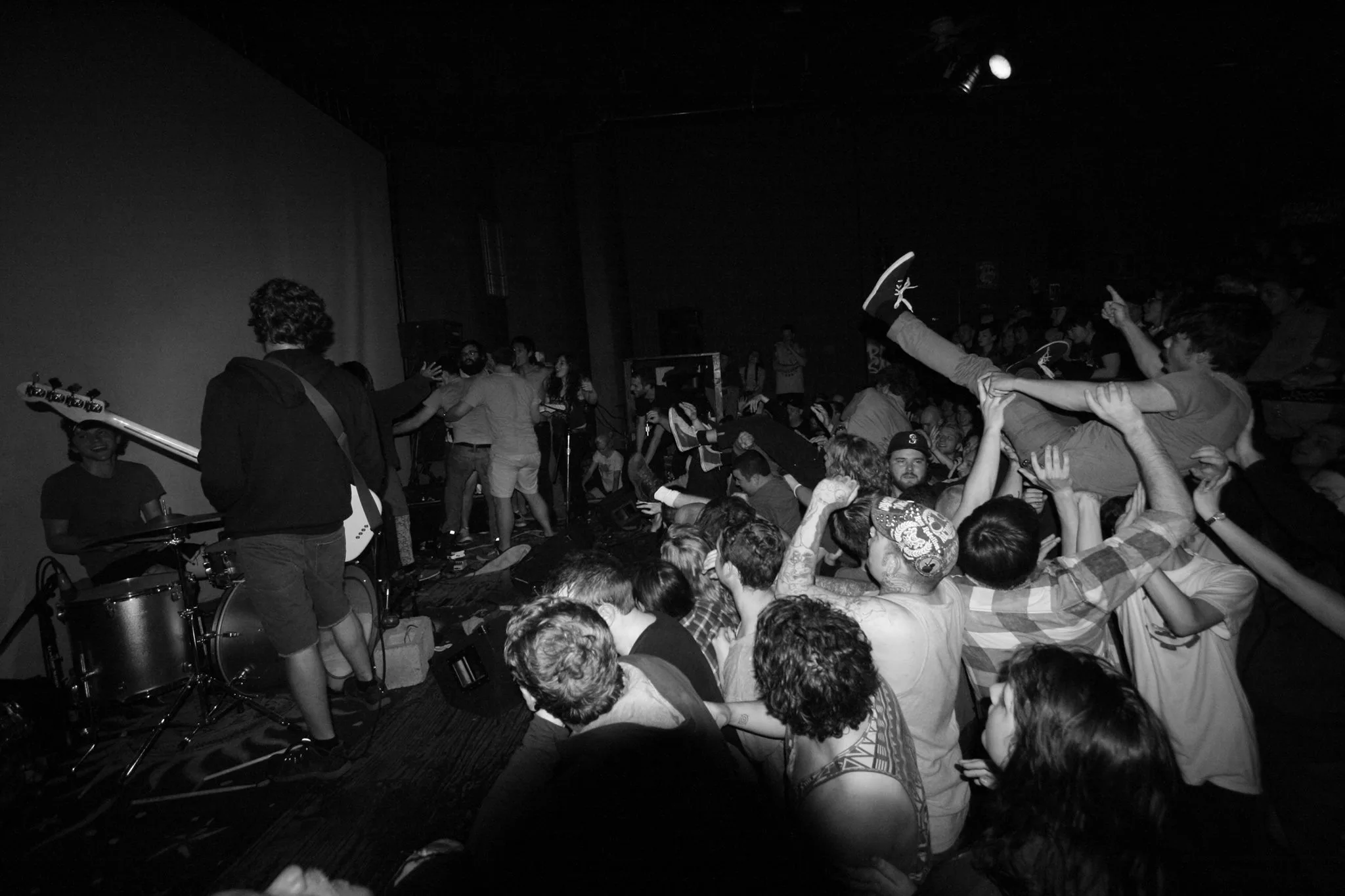 A black and white photo of someone crowd surfing during a metal performance