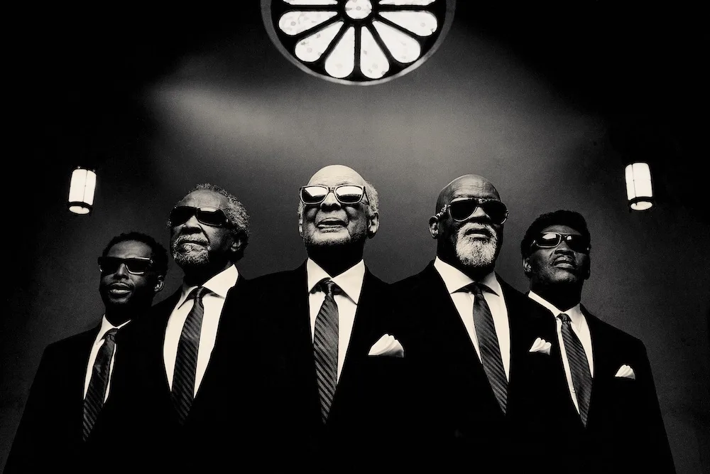 A black-and-white photo of The Blind Boys of Alabama wearing suits