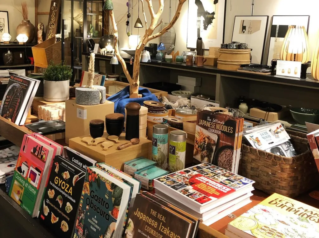 A display at KOBO with books, kitchen items, homegoods, and other gifts with a bare tree with bells behind it