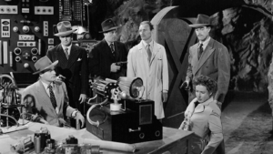 A black-and-white screencap from King of the Rocket Men. A group of people gather in an underground lair.