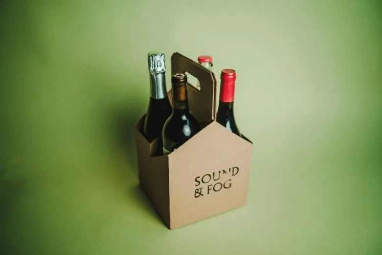 A cardboard case of four different drinks, including wine and beer.