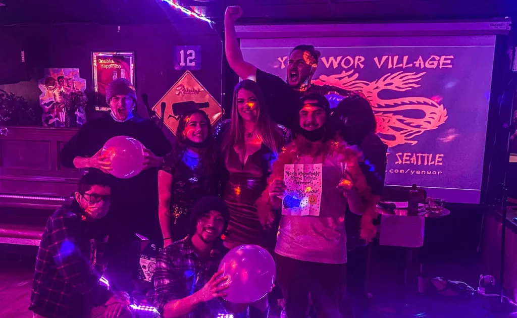 A group of trivia winners at Yen Wor Village in a purple-lit room.