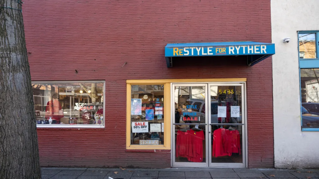 A brick storefront for ReStyle for Ryder on Ballard Ave with a blue overhanging sign