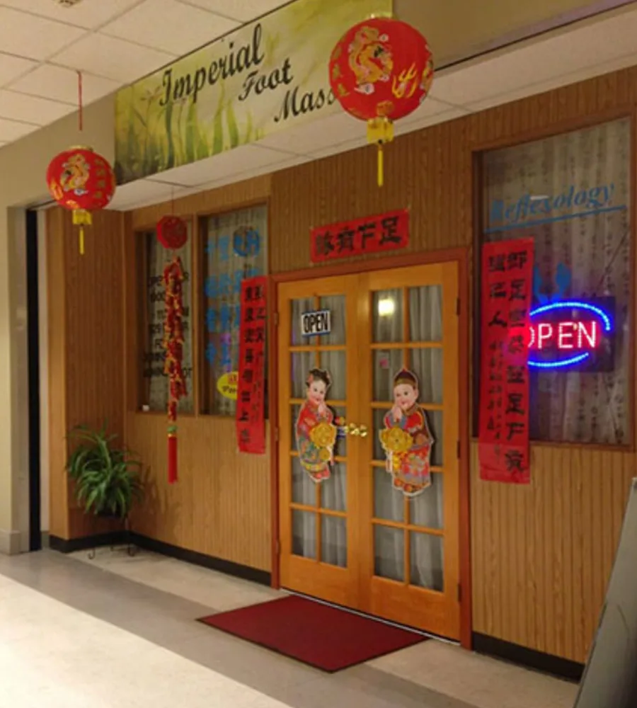 The storefront for Imperial Foot Massage with lanterns and red flags around a wooden door