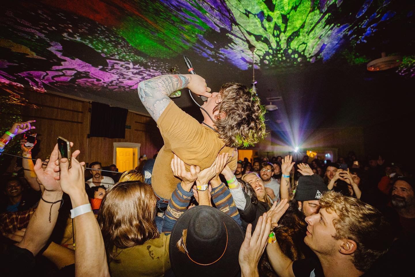 The singer from the band Monsterwatch crowdsurfs during Freakout Festival in a psychedilic-lit room