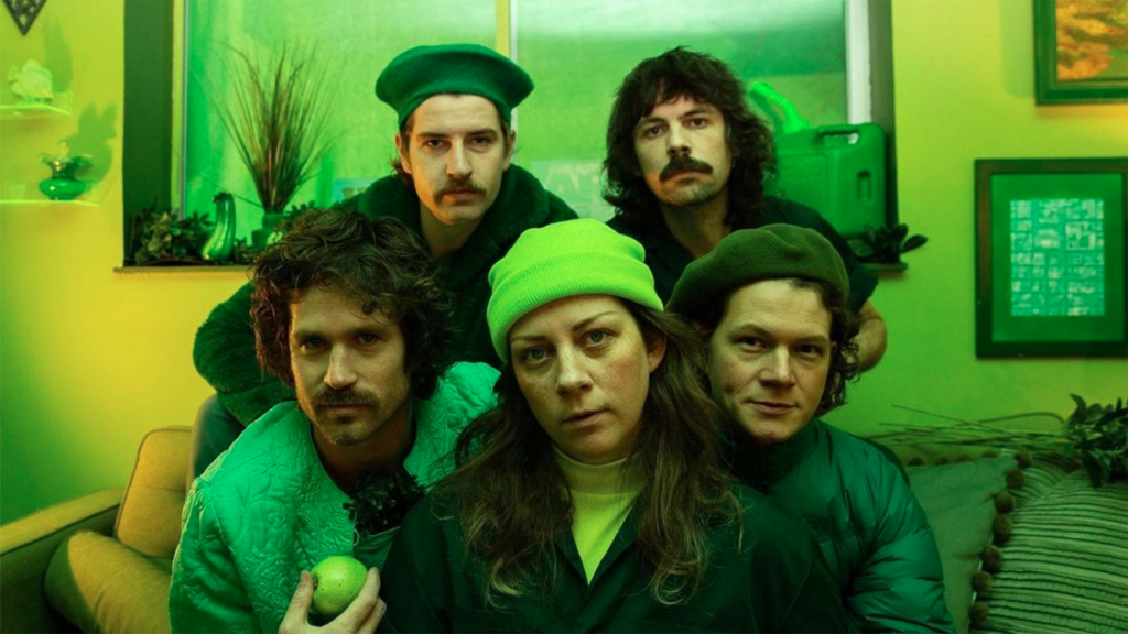 The band Telehealth posing together clad in all-green in a greenlit room