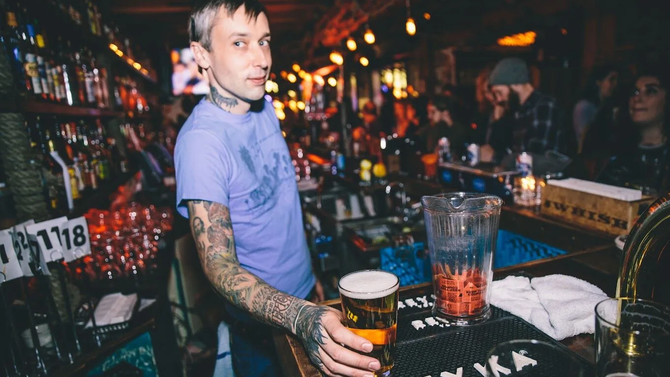A bartender at The Octopus Bar serving a drink in a crowded room