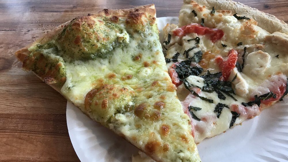 A slice of the pesto pizza from Hot Mama's Pizza on a plate with another slice