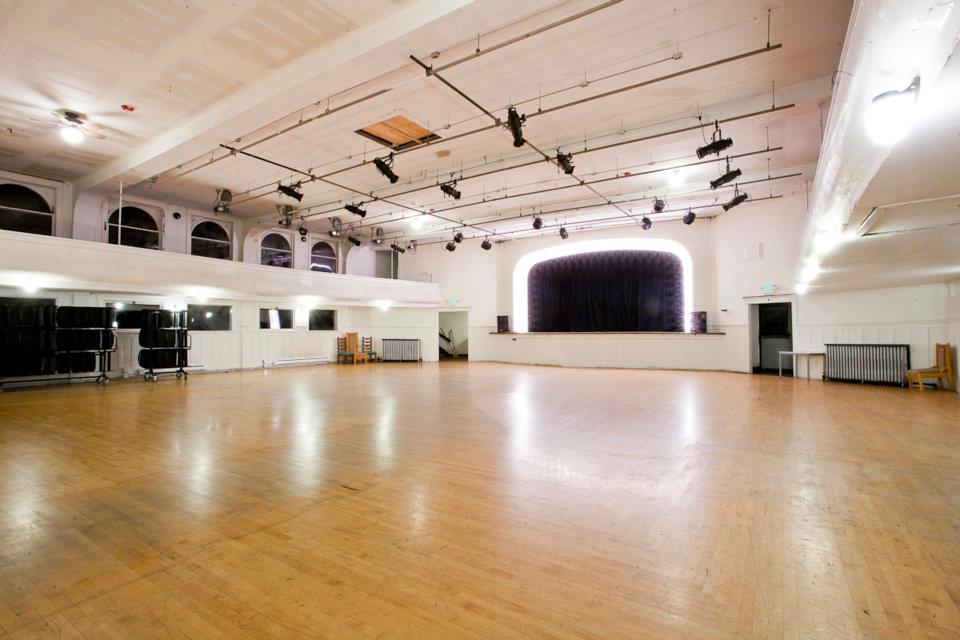 An interior shot of Washington Hall with a large room and empty stage with lights around it