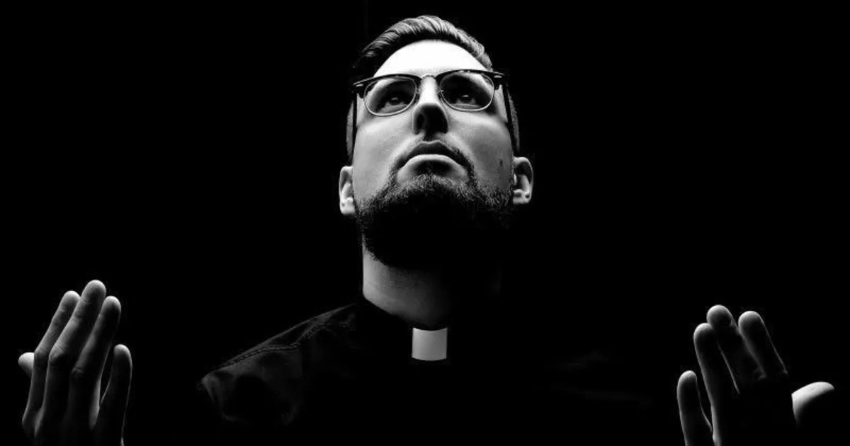Tchami holds his hands up in prayer while wearing a priest costume
