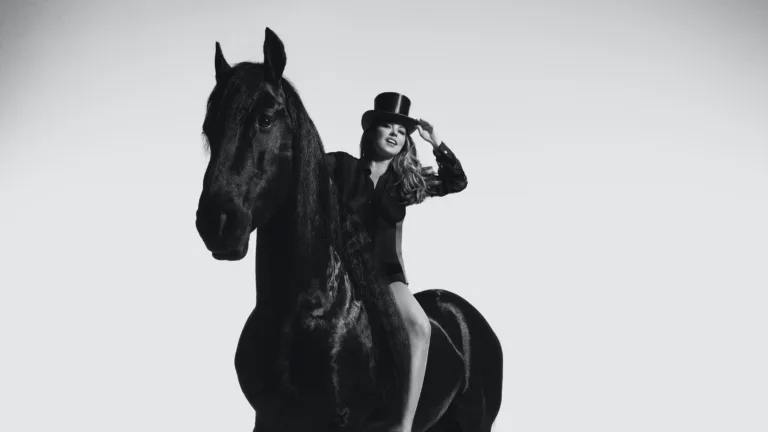 Shania Twain rides on a black horse in a black and white photo