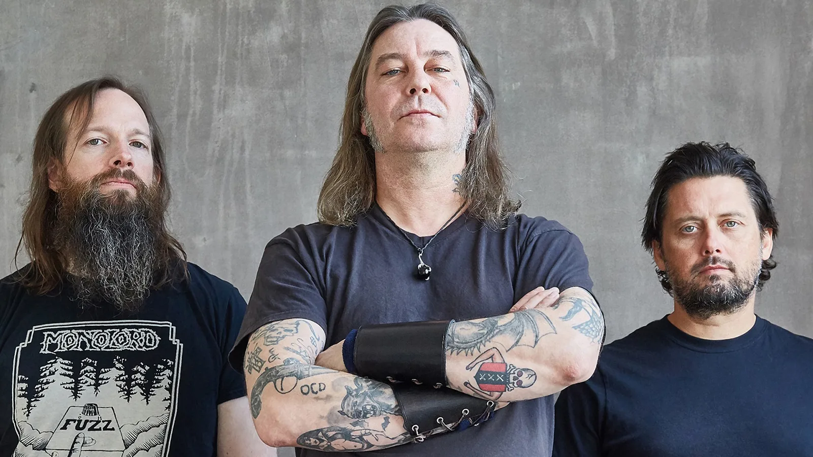The members of High on Fire, guitarist/vocalist Matt Pike, bass player George Rice, and drummer Des Kensel, pose side by side.