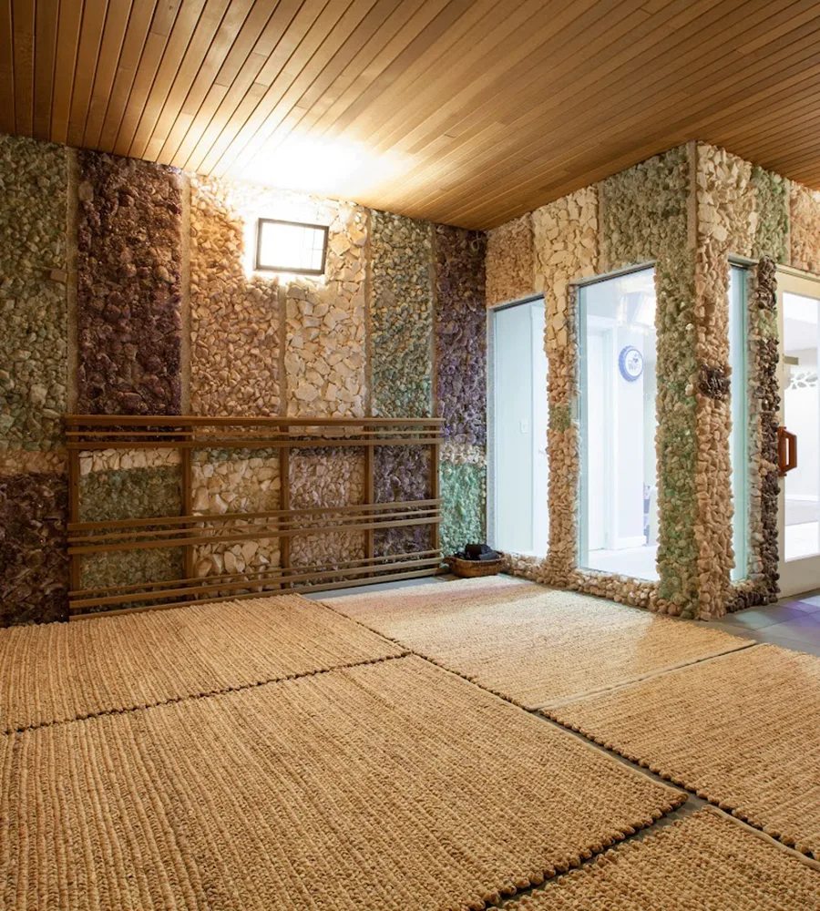 The Jade Room at Q Sauna & Spa. Woven mats lie on the floor and the room is softly lit by wall lantern sconces.