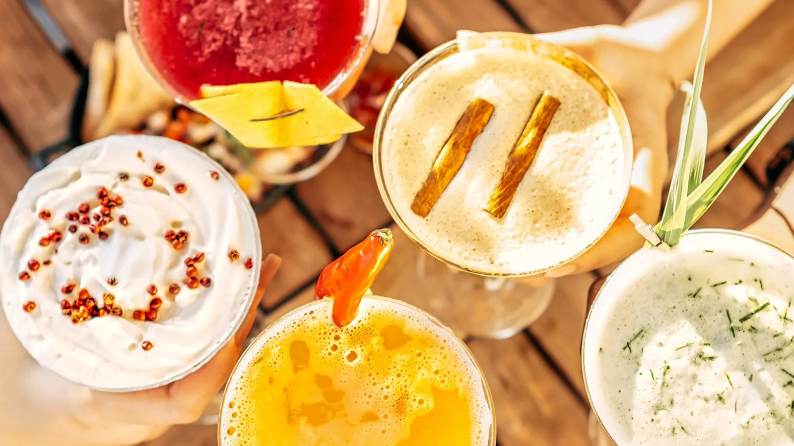 An overhead shot of people cheersing with wildly different cocktails.