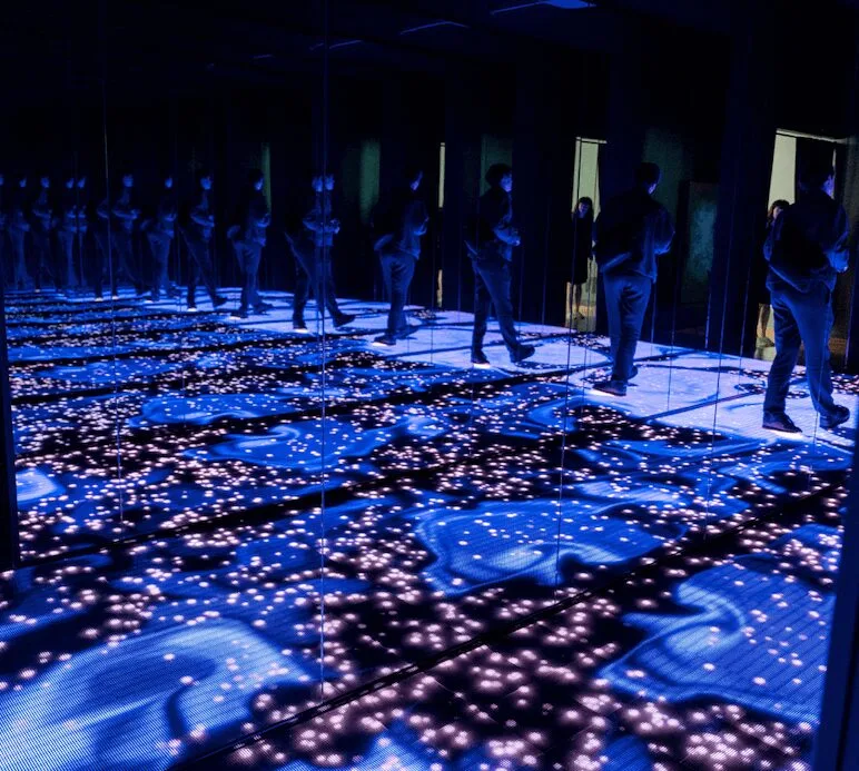 A room of mirrors and lights. The floor responds to touch. It feels like infinity.