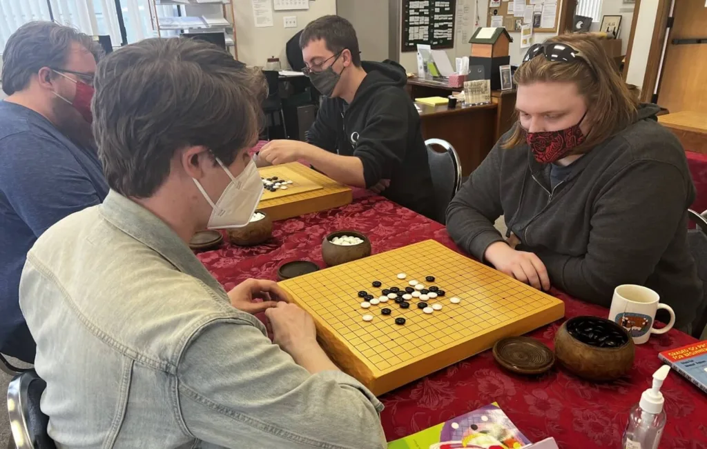 Two people play Go at the Seattle Go Center wearing masks