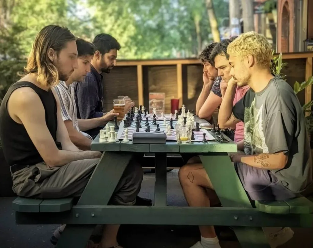 Four people sit and play chess at Kings Hardware