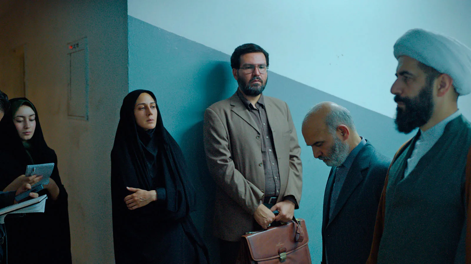 A still from Holy Spider. A group of people, including actress Zar Amir Ebrahimi, who plays the investigative journalist gather in a hallway