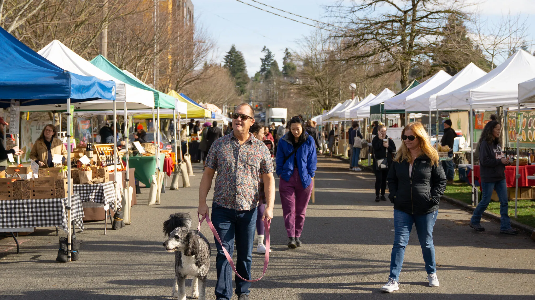 A group of people walk through the Columbia City Farmer's Market.