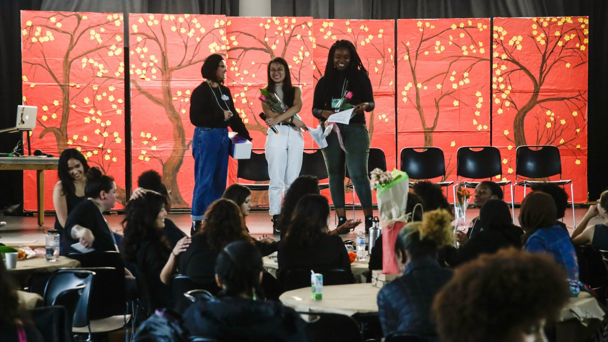 A group of young people stand onstage presenting at Girlvolution