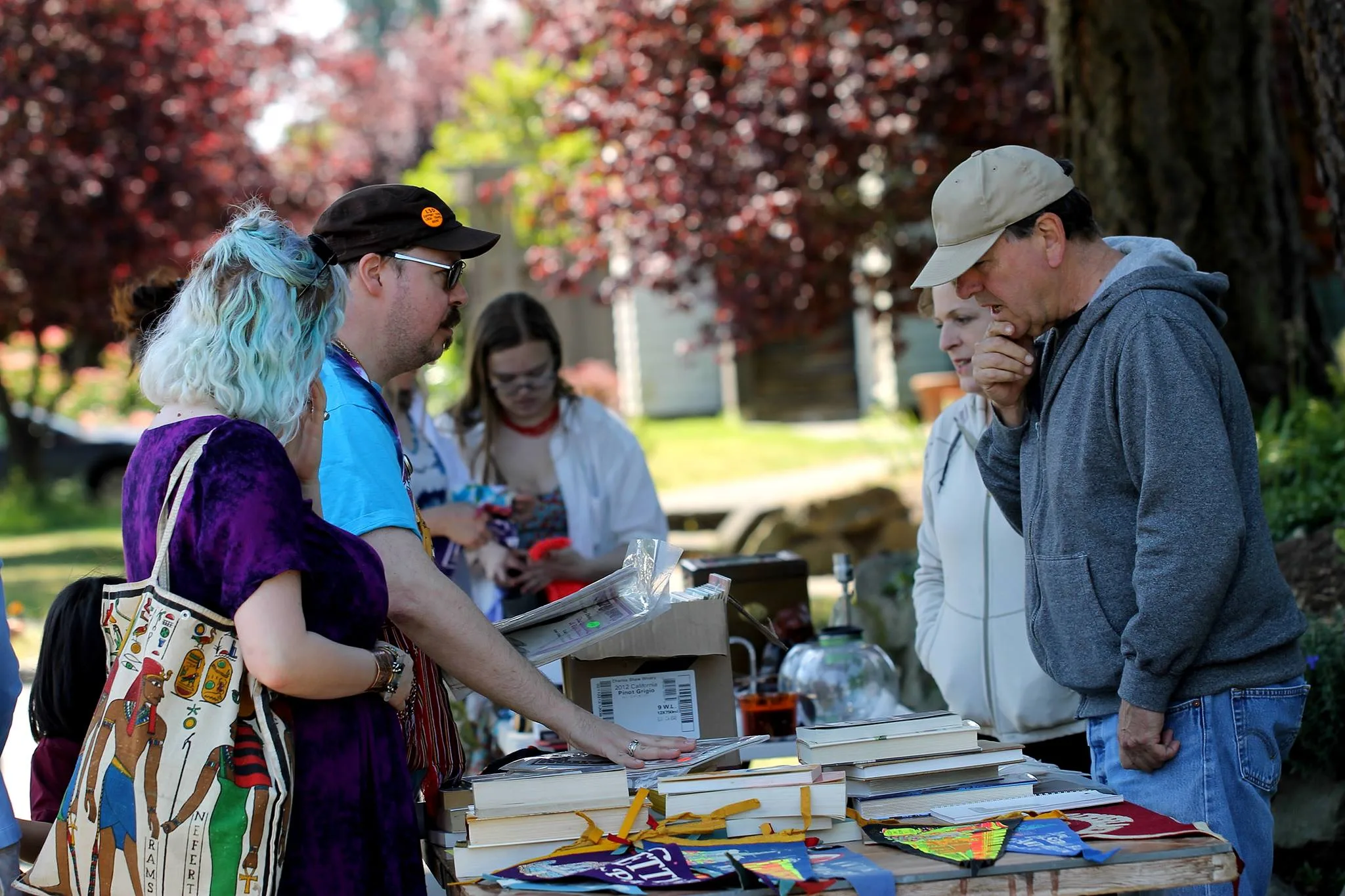 A man and woman discuss prices of books with a vendor at the Phinneywood Garage sale