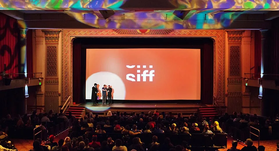 A crowd sits inside a SIFF theatre as three people line up onstage