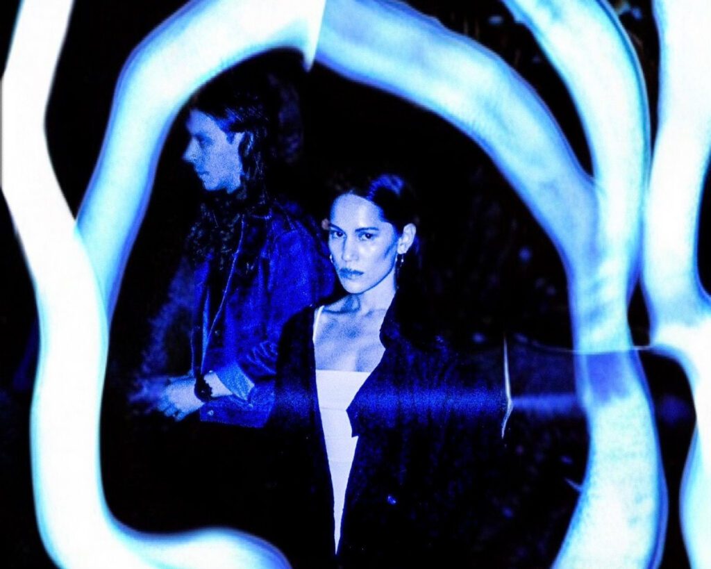 The lead singer of NAVVI stands in the center of a blue image with image blurbs swirling around her