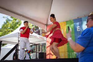 A performer dances on a colorful rainbow stage at PrideFest