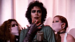 A still from Rocky Horror Picture Show featuring Frank-N-Furter looking surprised at the camera