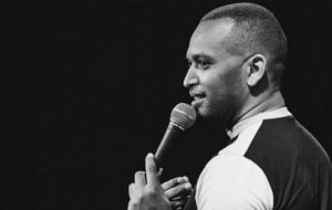 Solomon Georgio looks out at the crowd while holding a mic in a black and white photo