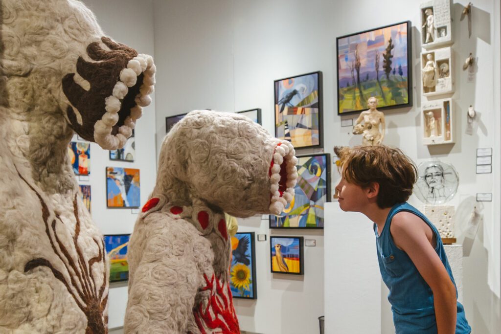 A child looks into the mouth of an art creature with curiosity at the Seattle Art Fair.