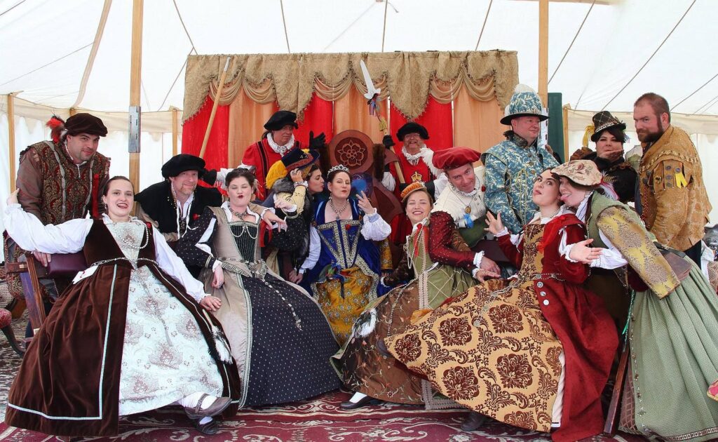A large group of people dressed in renaissance wear pose for a picture